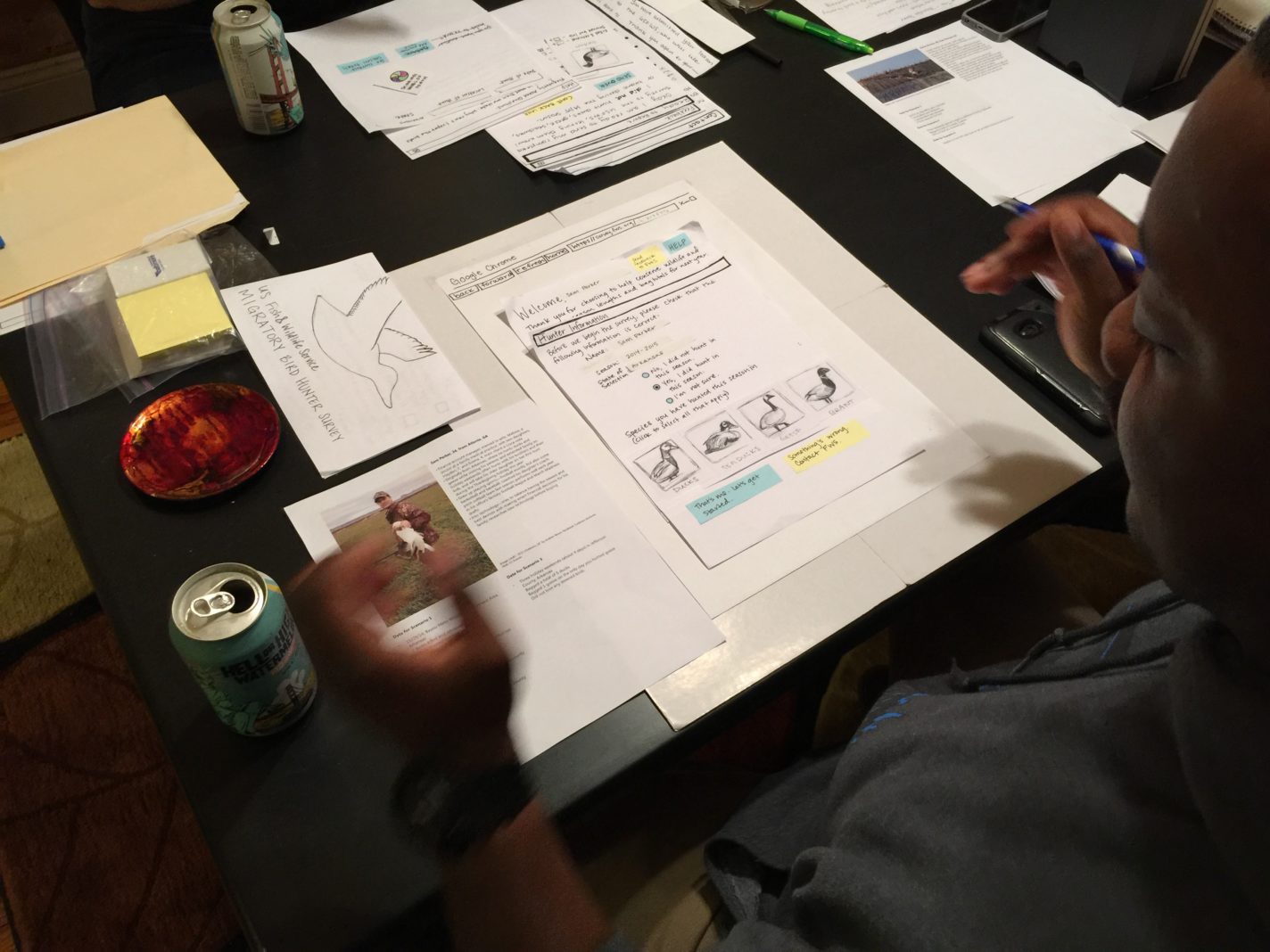 A black male waterfowl hunter interacting with the paper prototype and explaining his process and choices