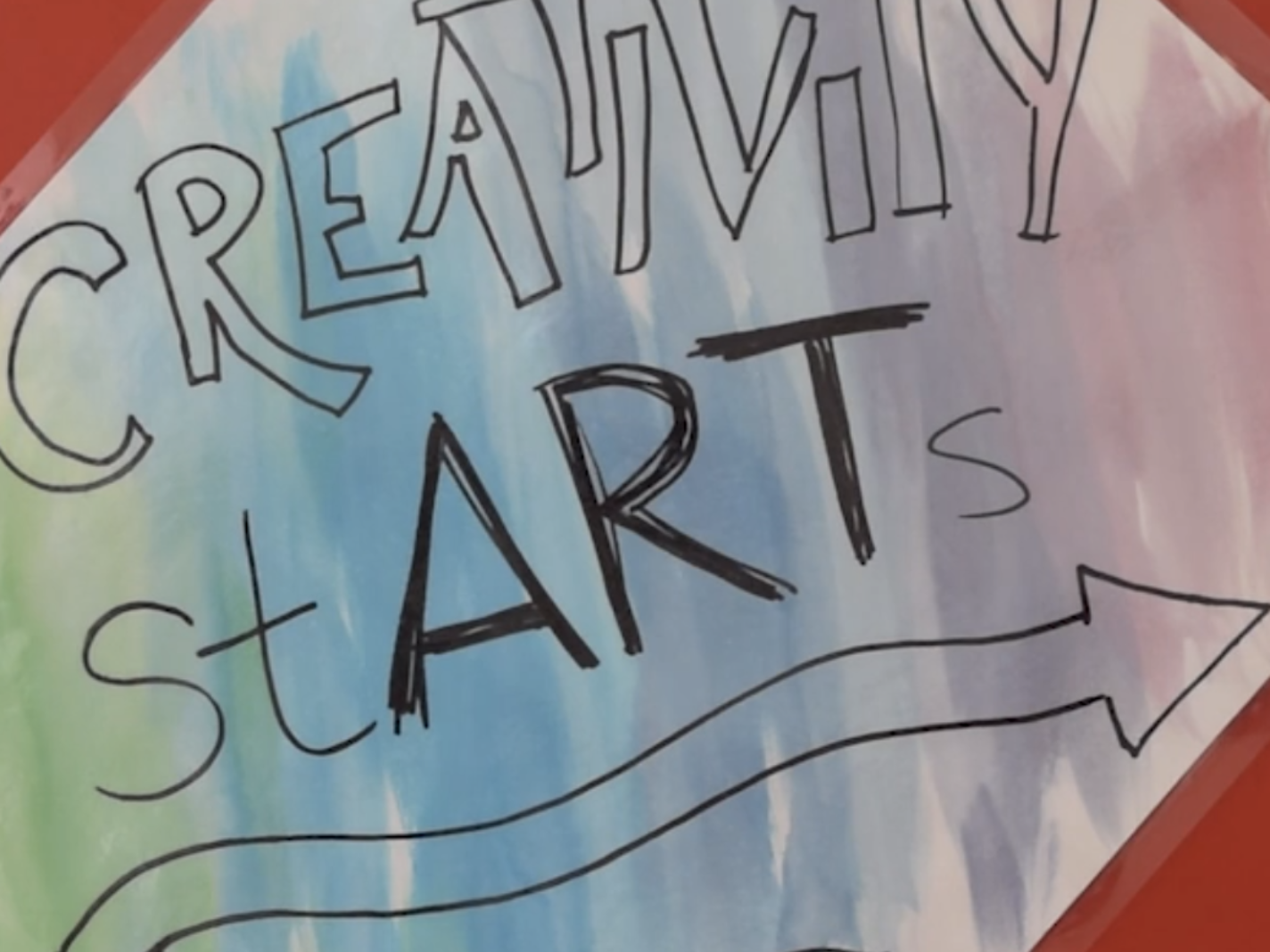 A screenshot from a Vimeo video of a red metal storage container with a paper attached saying "Creativity StARTS here"