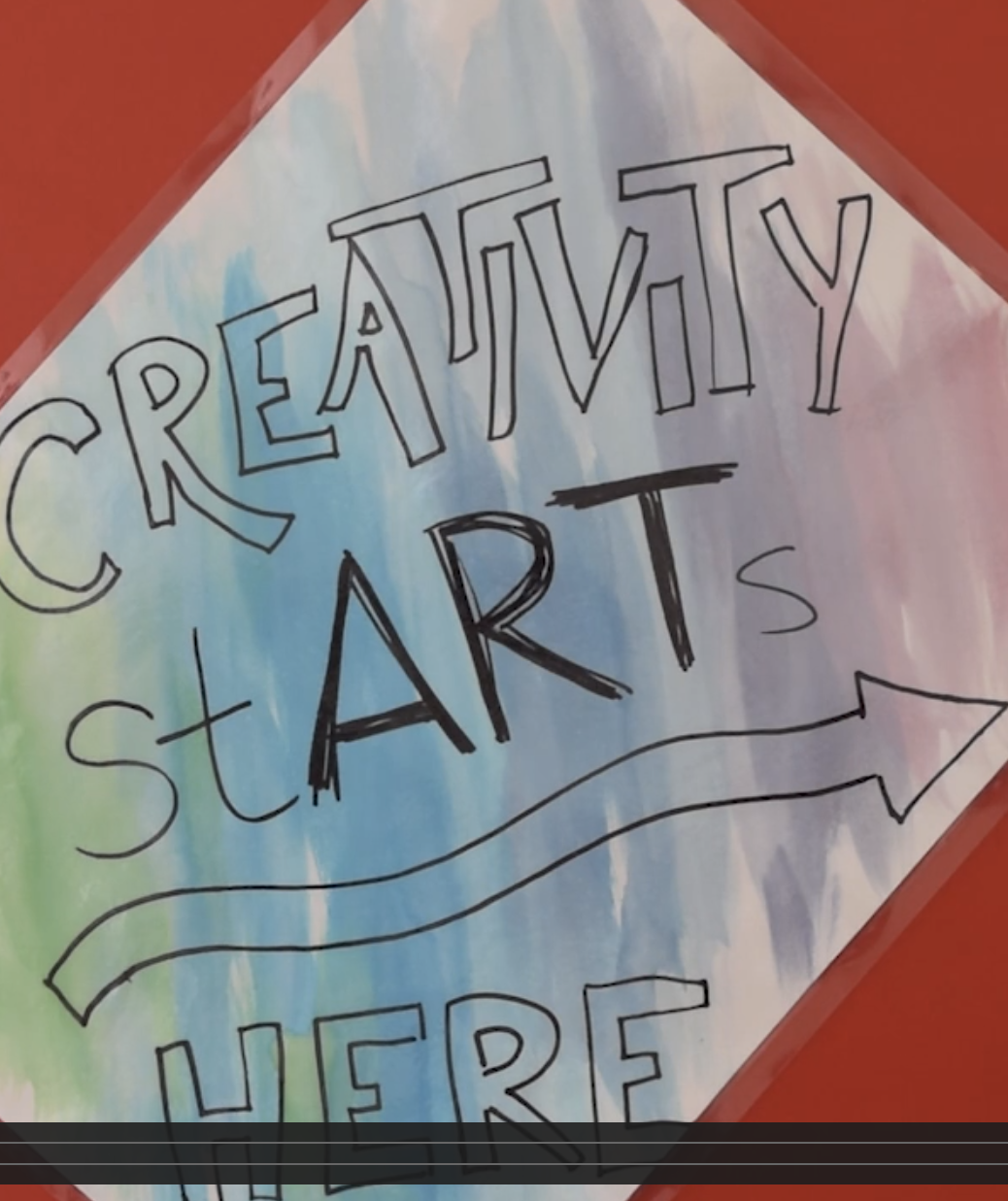 A screenshot from a Vimeo video of a red metal storage container with a paper attached saying "Creativity StARTS here"